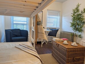Una habitación acogedora con una cama, una silla, una mesa y un radiador.