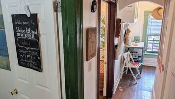 A hallway with a chalkboard sign, a door, and a glimpse of a room with a window and a table.