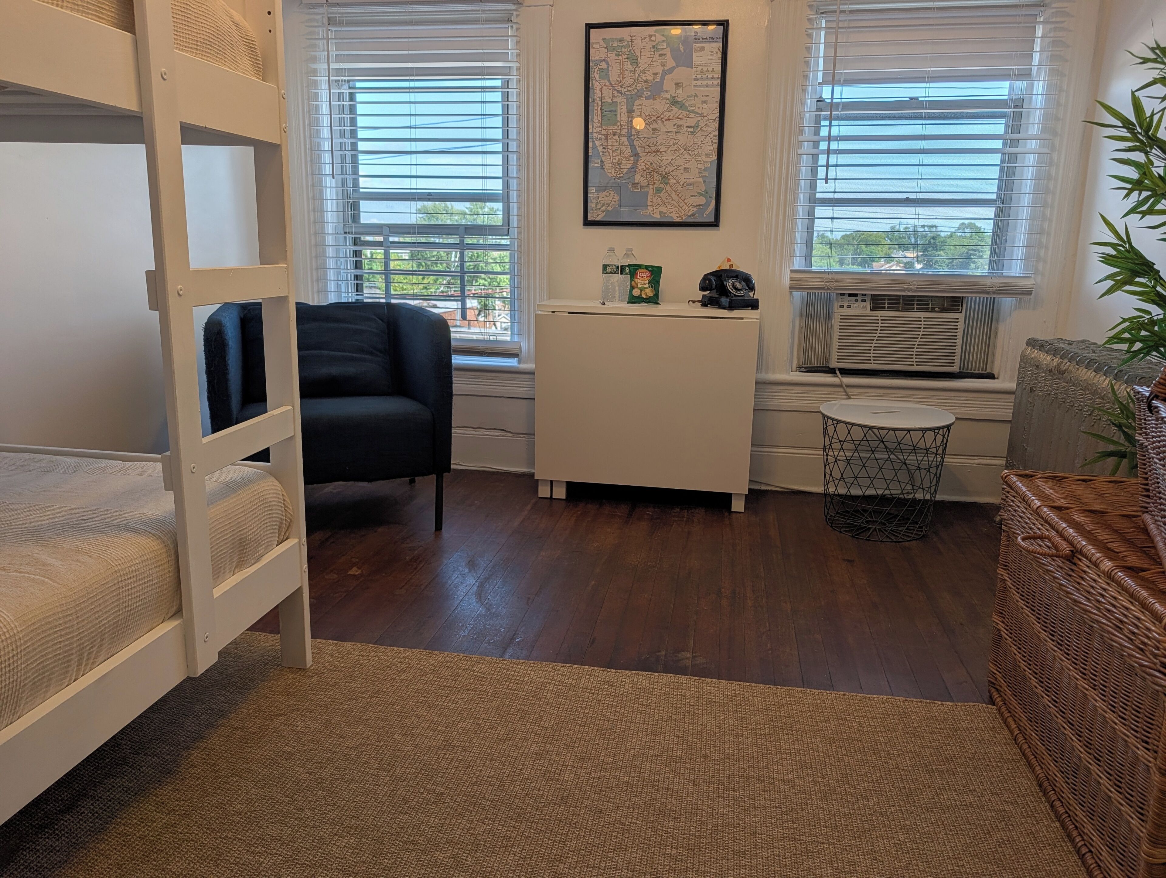 A room with bunk beds, a desk, a chair, and a window with blinds.