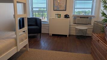 A room with bunk beds, a desk, a chair, and a window with blinds.
