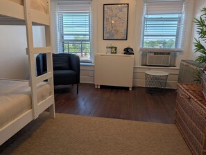 A room with bunk beds, a desk, a chair, and a window with blinds. - New York City with the Family—Your Home Base on Staten Island—Perfect for 2–4! (Staten Island)