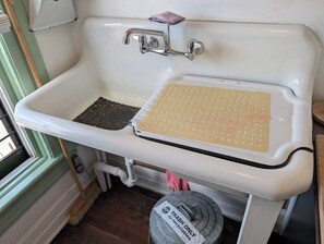 A white bathroom sink with a soap dish, a sponge, and a trash bin with a label. - New York City with the Family—Your Home Base on Staten Island—Perfect for 2–4! (Staten Island)