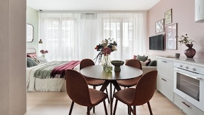 A modern kitchen with a dining area, a large window with sheer curtains, and a flat-screen TV mounted on the wall. - Studio 54, Holzera, Wilanów, Warsaw (Warszawa)