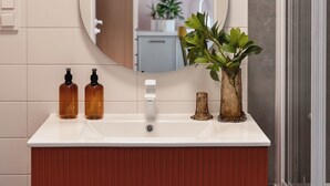A bathroom with a white vanity, a mirror, a shower, and a potted plant. - Studio 54, Holzera, Wilanów, Warsaw (Warszawa)