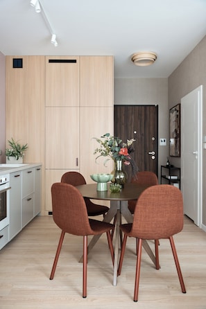 Eine moderne Küche mit Holzschränken, einem Esstisch mit vier Stühlen und einer Vase mit Blumen.
