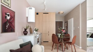 A modern living room with a sofa, a dining table with chairs, a kitchen area with cabinets, and a hallway leading to a bedroom. - Studio 54, Holzera, Wilanów, Warsaw (Warszawa)