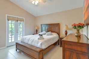 A bedroom with a bed, bedside tables, a bench, a dresser, and a door leading to a balcony. - Private Hot Tub & Dock! Hutchinson Island Retreat (Fort Pierce)