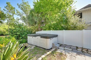A hot tub in a backyard with a white fence, surrounded by lush greenery and a stone pathway. - Private Hot Tub & Dock! Hutchinson Island Retreat (Fort Pierce)
