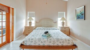 Une chambre à coucher avec un lit, deux tables de chevet, une fenêtre et une porte.