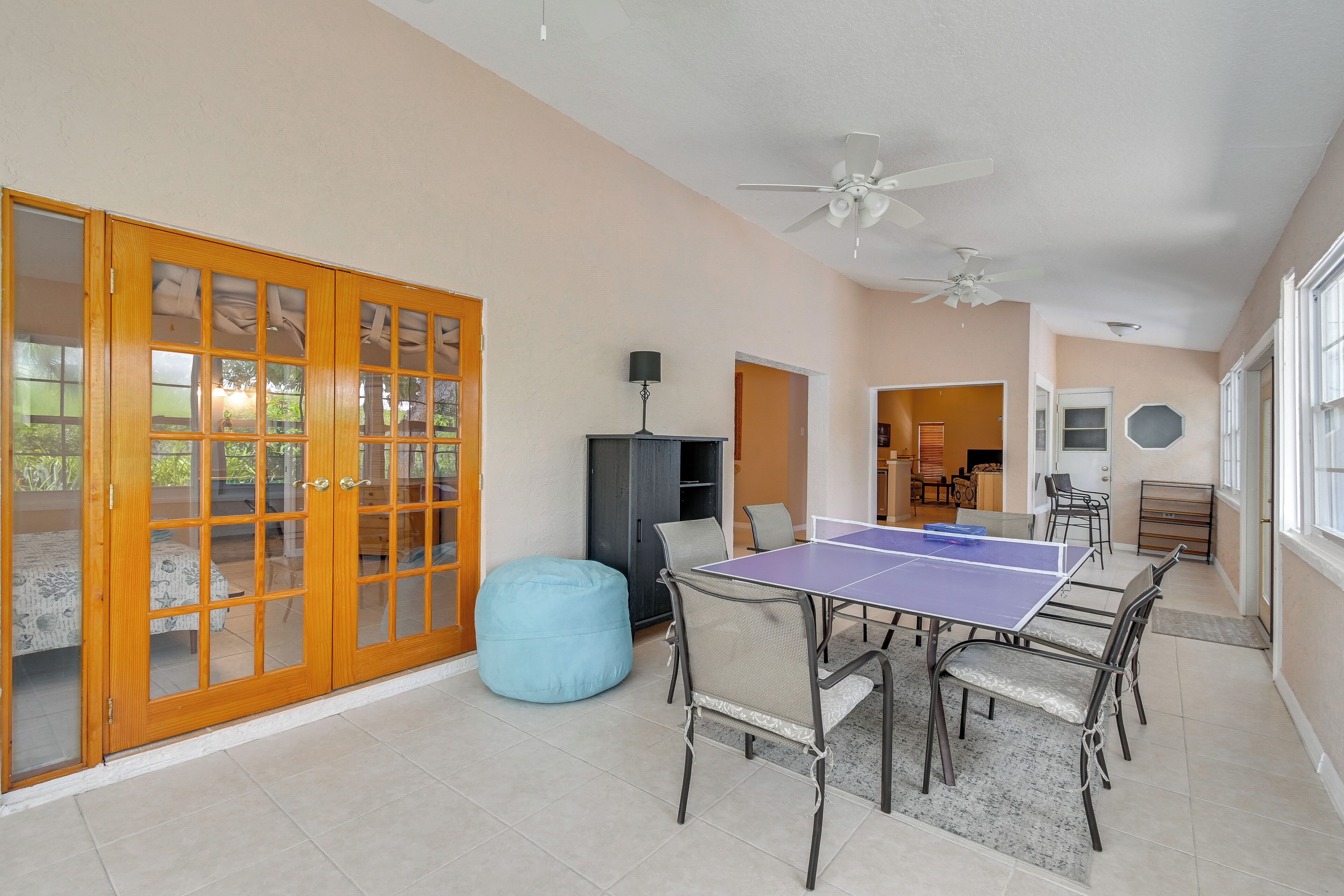 A spacious room with a ping pong table, a blue bean bag, and a ceiling fan.