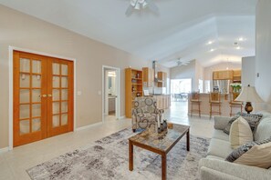 A spacious living area with a large wooden door, a patterned armchair, a coffee table, and a sofa with decorative pillows. - Private Hot Tub & Dock! Hutchinson Island Retreat (Fort Pierce)