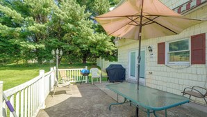 A patio with a table and chairs, a barbecue grill, and a covered umbrella. - Patio + Yard: Extended Escape in Hudson Valley! (Highland)