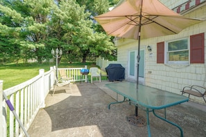 Een terras met een tafel, stoelen, een barbecue en een overdekte parasol.