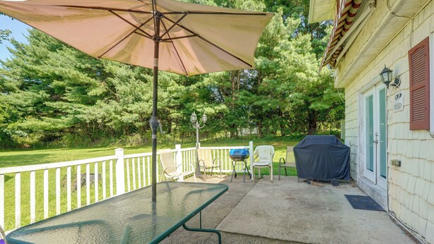An outdoor patio with a table and chairs, a barbecue grill, and a covered grill area. - Patio + Yard: Extended Escape in Hudson Valley! (Highland)