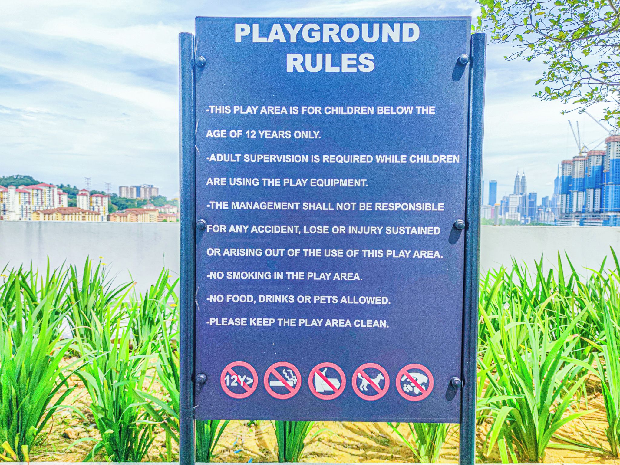 Spielplatzregeln Schild mit einer Stadtkulisse im Hintergrund.