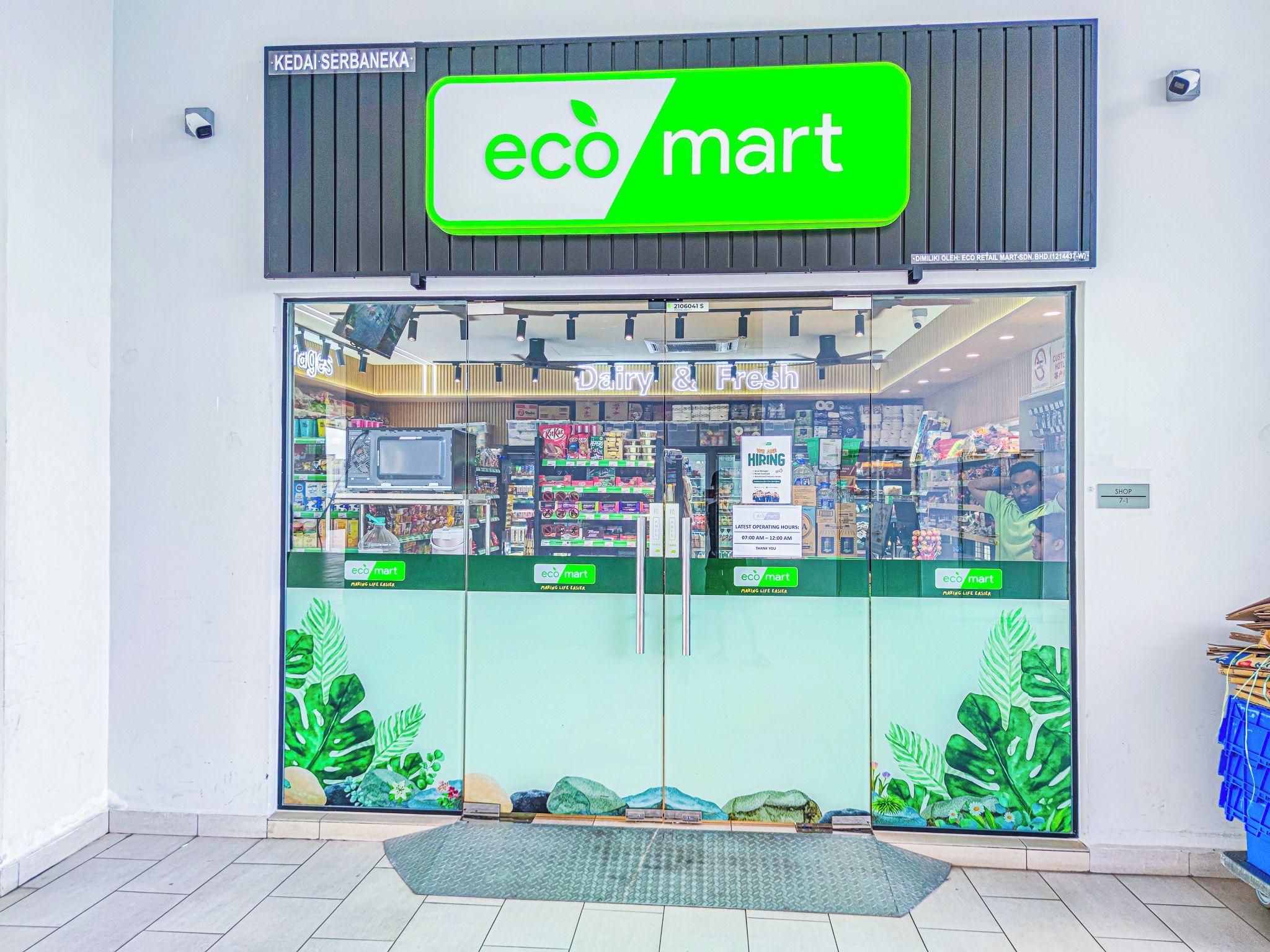 Ingången till en ekologisk butik med en grön logotyp, glasdörrar och en vy över butikens interiör, där hyllorna är fyllda med produkter.