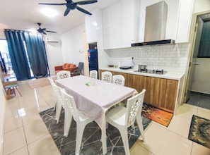 Une cuisine moderne avec des meubles blancs, une table à manger avec des chaises et un ventilateur de plafond.