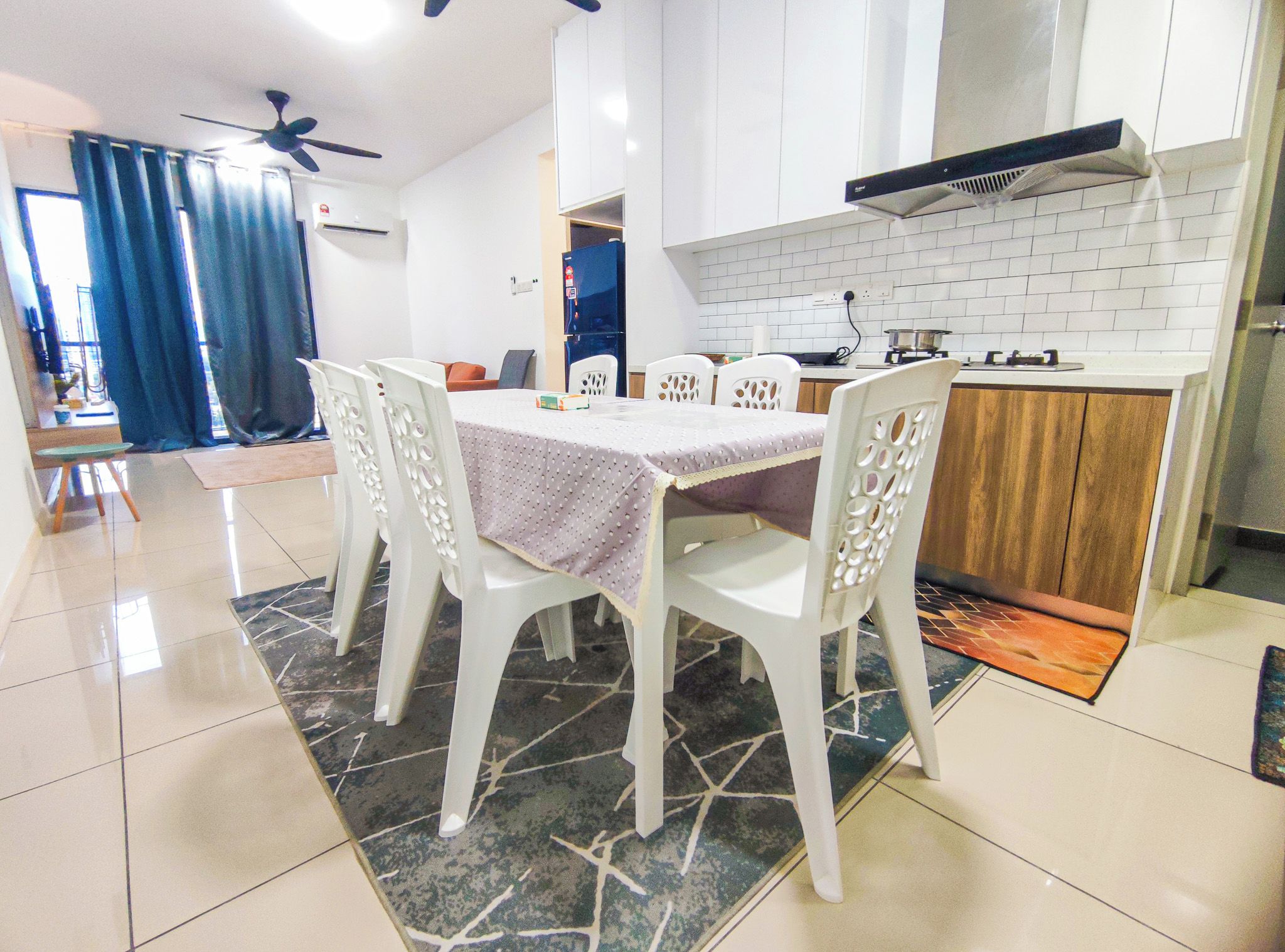 A modern kitchen with white cabinets, a black range hood, and a dining area with a table and chairs.