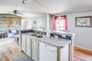 A kitchen with a marble countertop, a built-in dishwasher, and a ceiling fan.