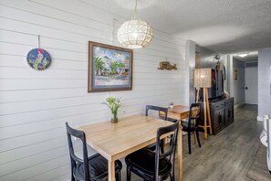 Ein Essbereich mit Holztisch und Stühlen, einer Pendelleuchte und einem gerahmten Gemälde an der Wand.