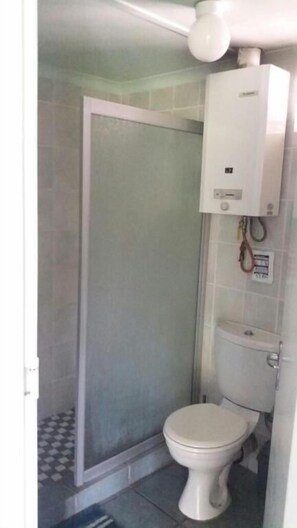 Un baño con inodoro, cabina de ducha y calefactor de pared.