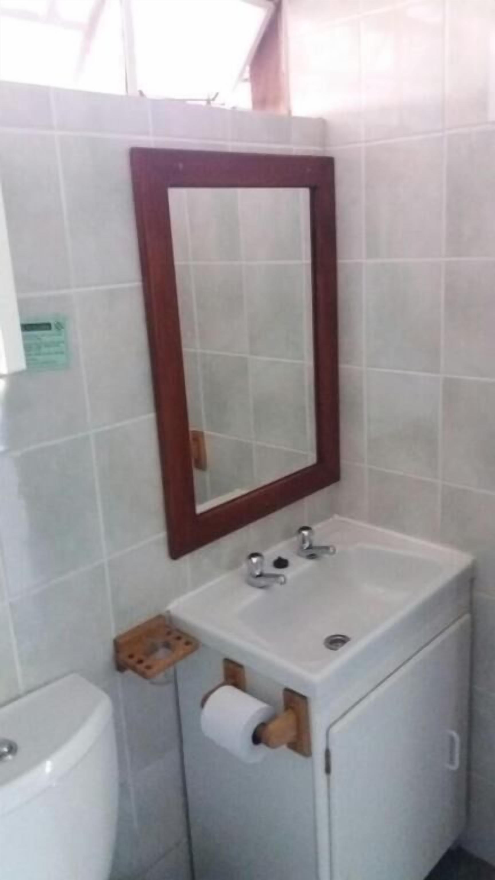 Een badkamer met een witte wastafel, een spiegel met houten lijst en een toilet.