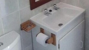 Une salle de bain avec un lavabo blanc, un miroir avec un cadre en bois et des toilettes.