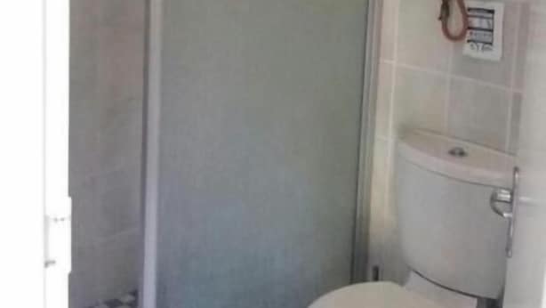 Une salle de bain équipée de toilettes, d’une cabine de douche et d’un radiateur fixé au mur.