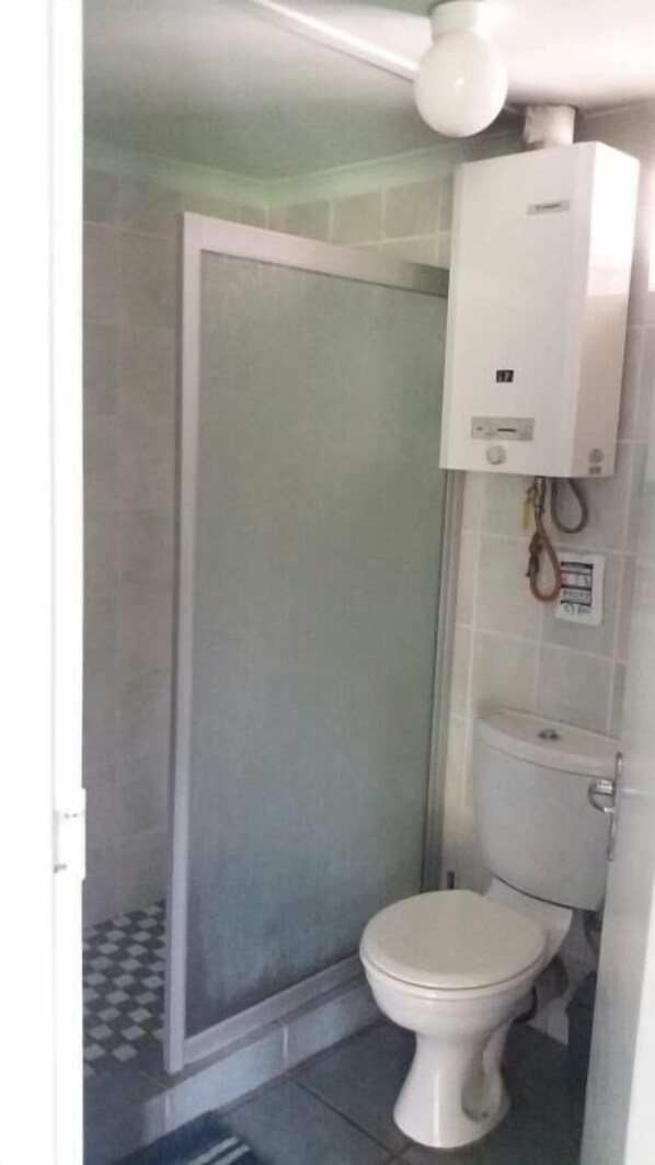 Un bagno con il water, una cabina doccia e un riscaldatore a parete.