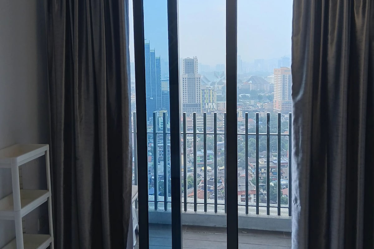 Ein Hotelzimmer mit einer großen Glasschiebetür, die auf einen Balkon mit Blick auf die Stadt führt.