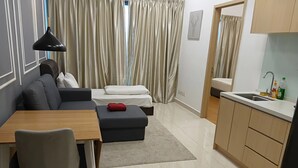 A modern living space with a sofa, ottoman, dining table, and a kitchen area with a sink. - Infinitum by colony  (Kuala Lumpur)