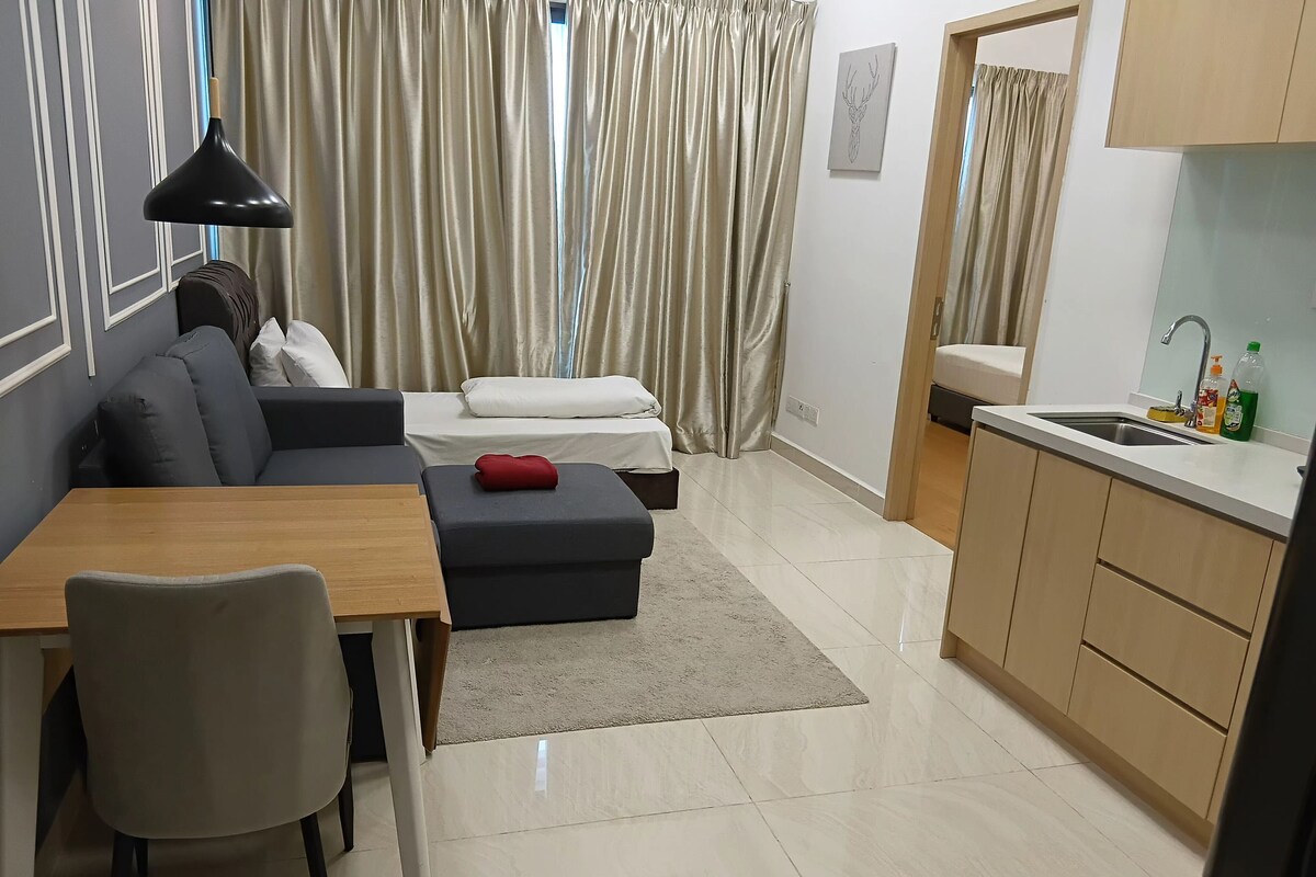 Ein moderner Wohnraum mit Sofa, Hocker, Esstisch und einer Küchenzeile mit Spüle.