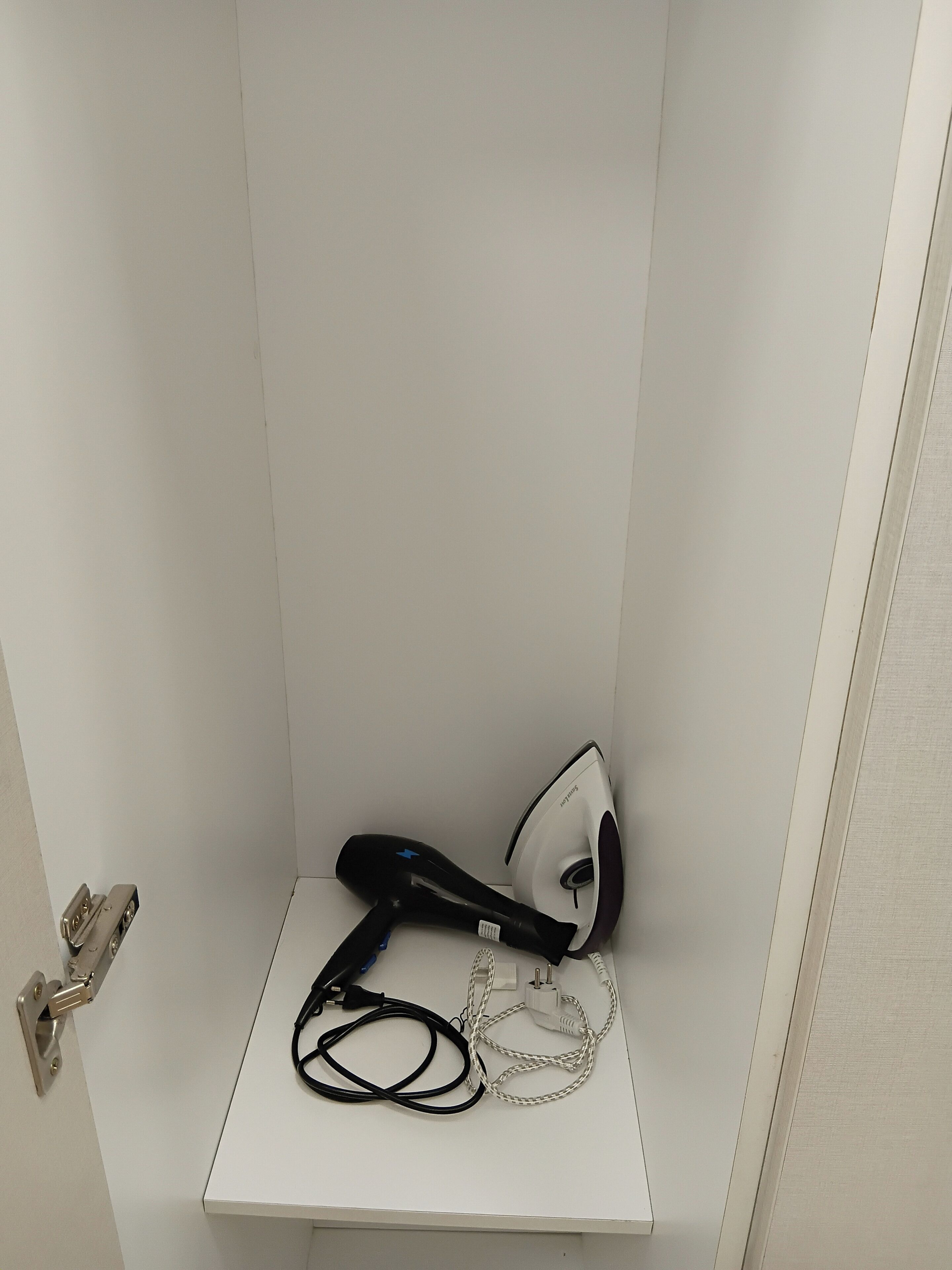 A white shelf with a hairdryer and an iron.