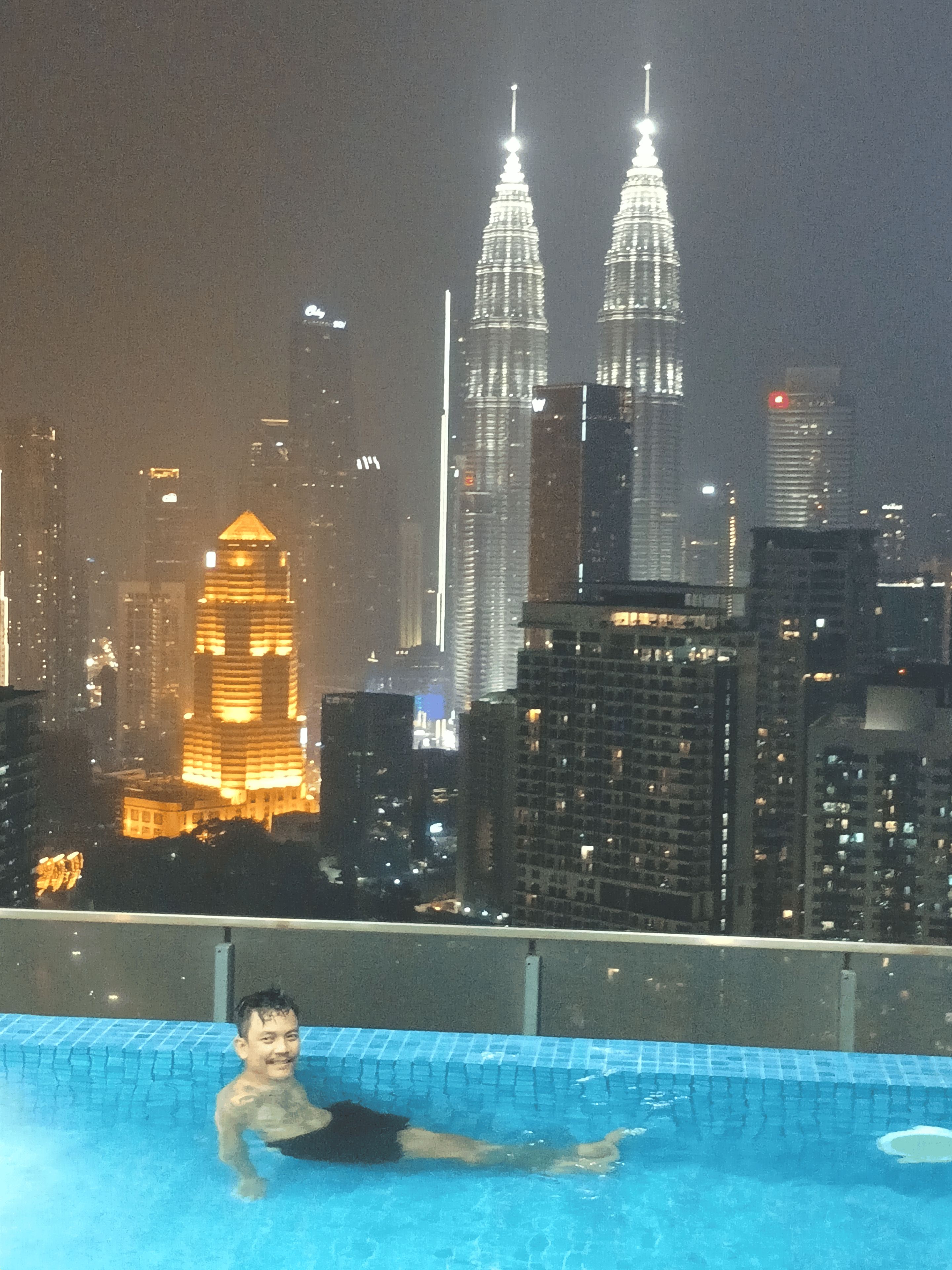 A person in a swimming pool with a cityscape in the background.