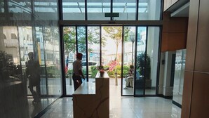 A reception area with a marble counter, glass doors leading outside, and a tiled floor. - Infinitum by colony  (Kuala Lumpur)