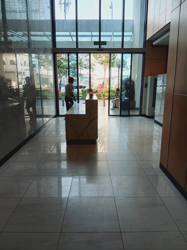 Una zona de recepción con mostrador de mármol, puertas de vidrio hacia el exterior y suelo de baldosas.