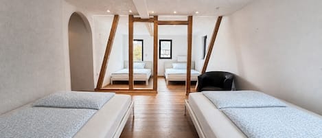 Una habitación con dos camas, una estructura de techo de madera y vista a otra habitación con una cama.
