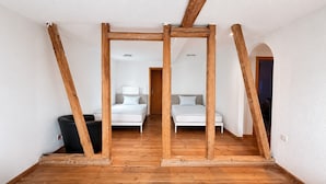 A room with a wooden floor, two beds, a black trash bin, and a white door. - Holiday Home 'Air Hockey, Home Cinema' with Wi-Fi (Eitelborn)
