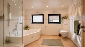 Ein modernes Badezimmer mit einer Duschkabine, einer freistehenden Badewanne, einer Toilette und einem Handtuchhalter.