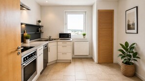A modern kitchen with a built-in oven, microwave, and a window above the sink.