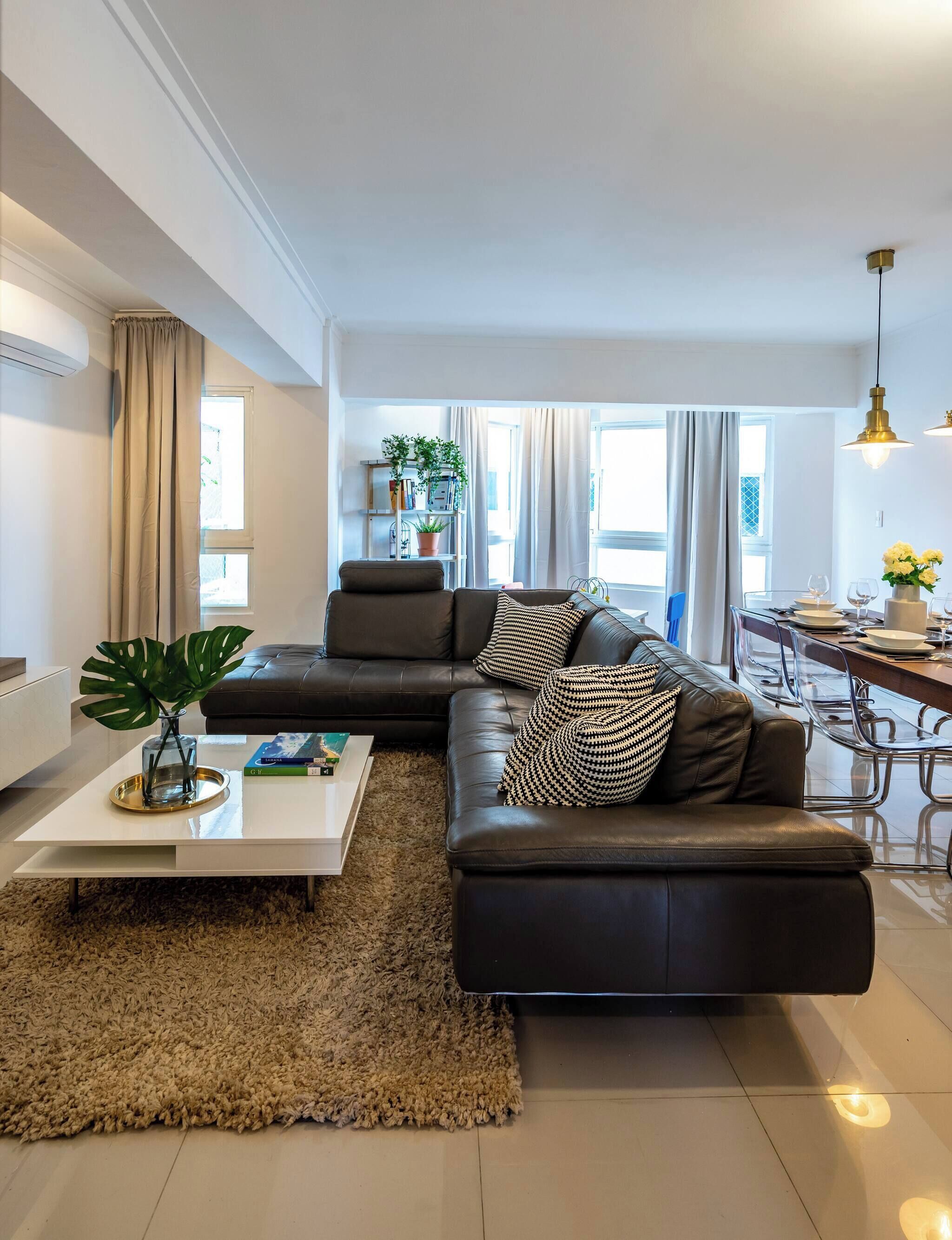 A modern living room with a sectional sofa, a coffee table, and a dining area with chairs.