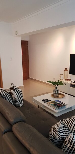 Un salon moderne avec un canapé, une table basse et un téléviseur.