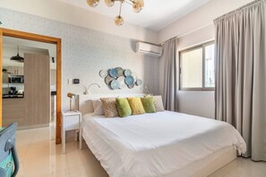 Een moderne slaapkamer met een groot bed, een nachtkastje, een wandairconditioner en uitzicht op de stad.