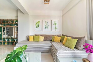 A modern living room with a sectional sofa, a glass coffee table, and a green plant. - Stylish Downtown KingBed 300mb fast wifi! (Santo Domingo)