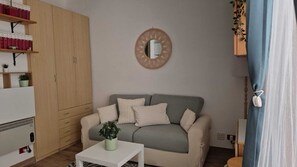 Una sala de estar con un sofá, una mesa de centro, una estantería y un espejo en la pared.