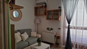 Una sala de estar con un sofá, una mesita, una lámpara y un aparador con puertas de vidrio.