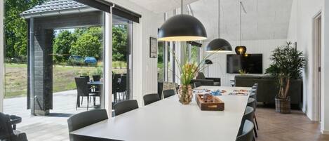 A modern dining area with a white table, black chairs, and pendant lighting.
