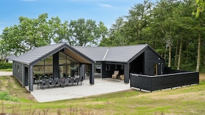 Ein modernes Haus mit einer großen Terrasse, einer Essgelegenheit und einer separaten Lounge.