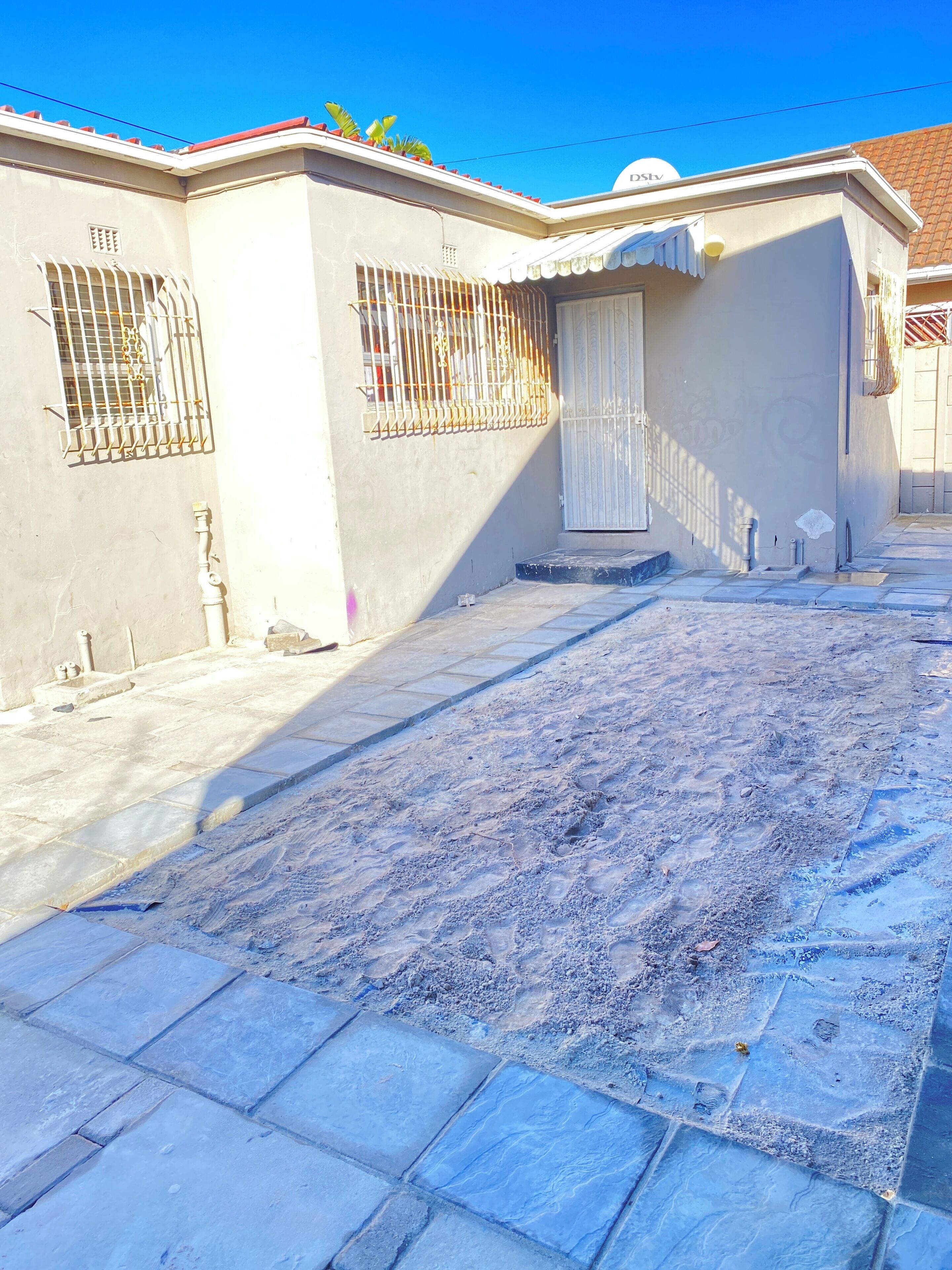 A building with a gated entrance, a small porch, and a paved area with footprints.