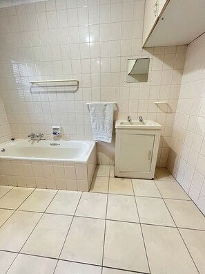 Et badeværelse med badekar, vask og spejl.